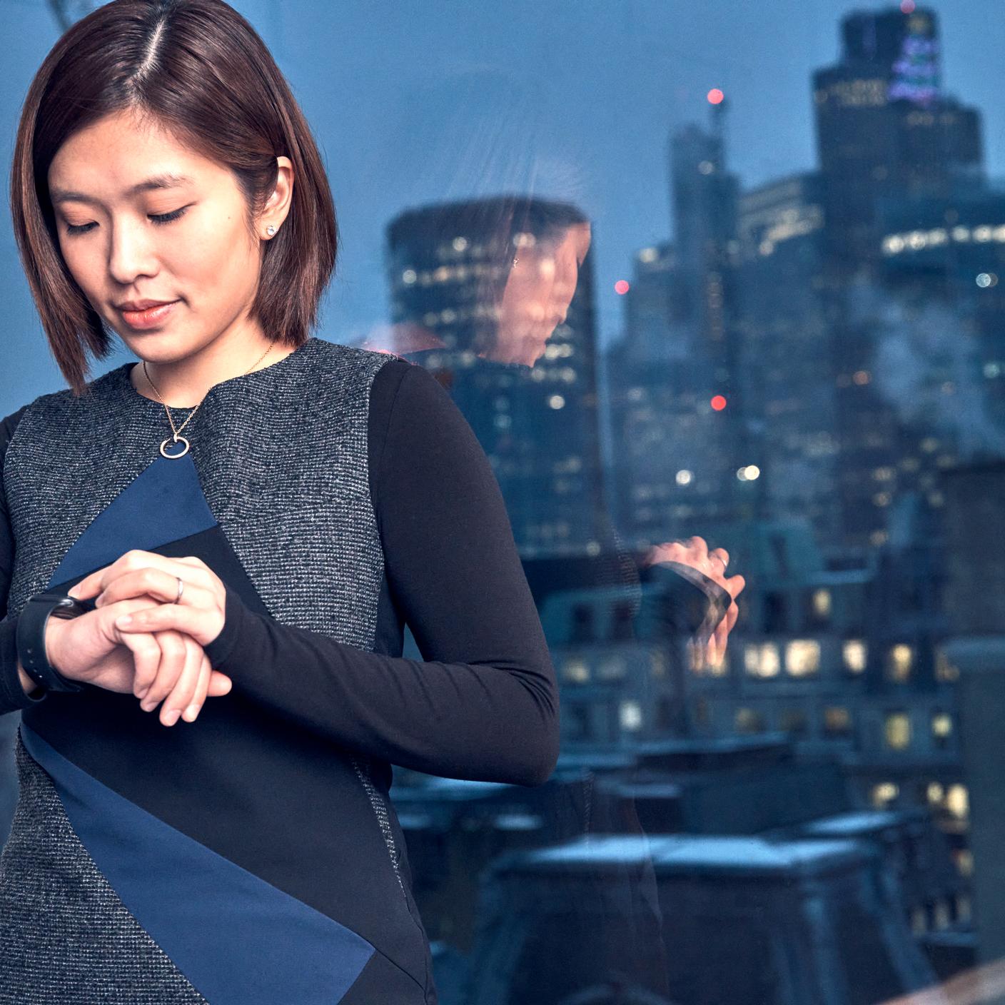 woman looking at digital watch in office in city at night