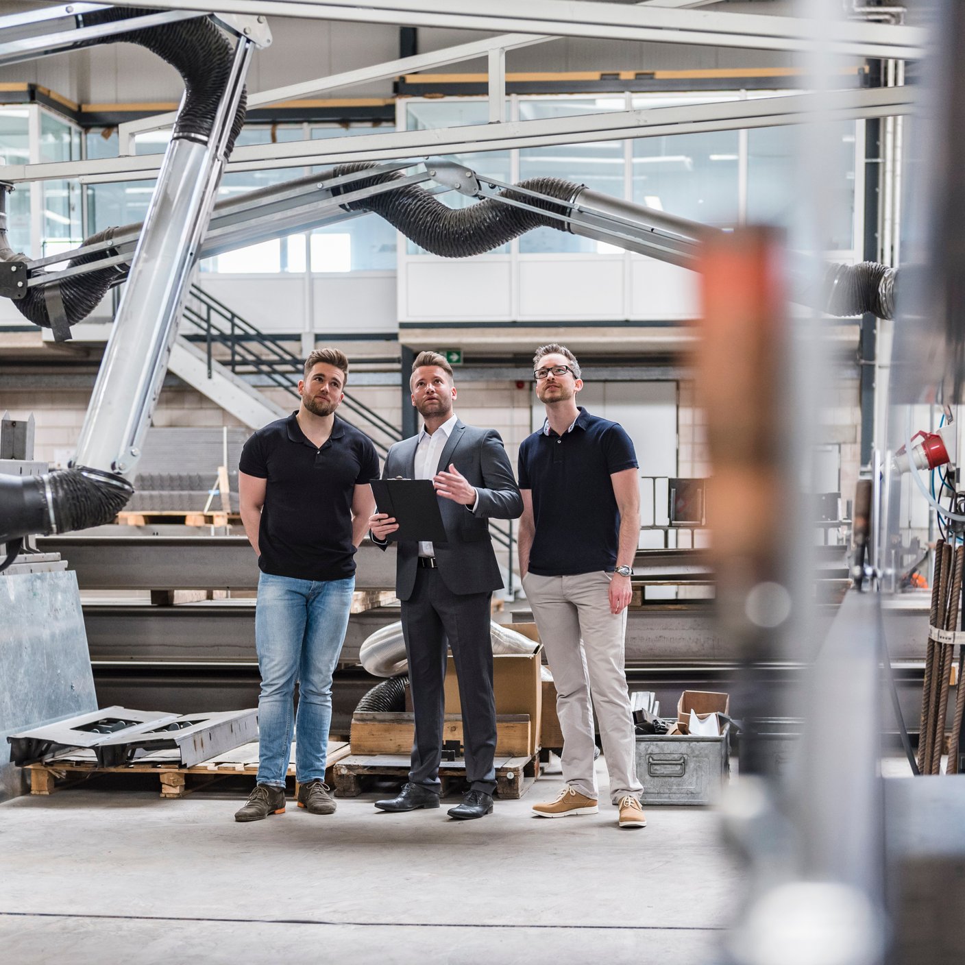 Three men standing and talking on factory shop floor