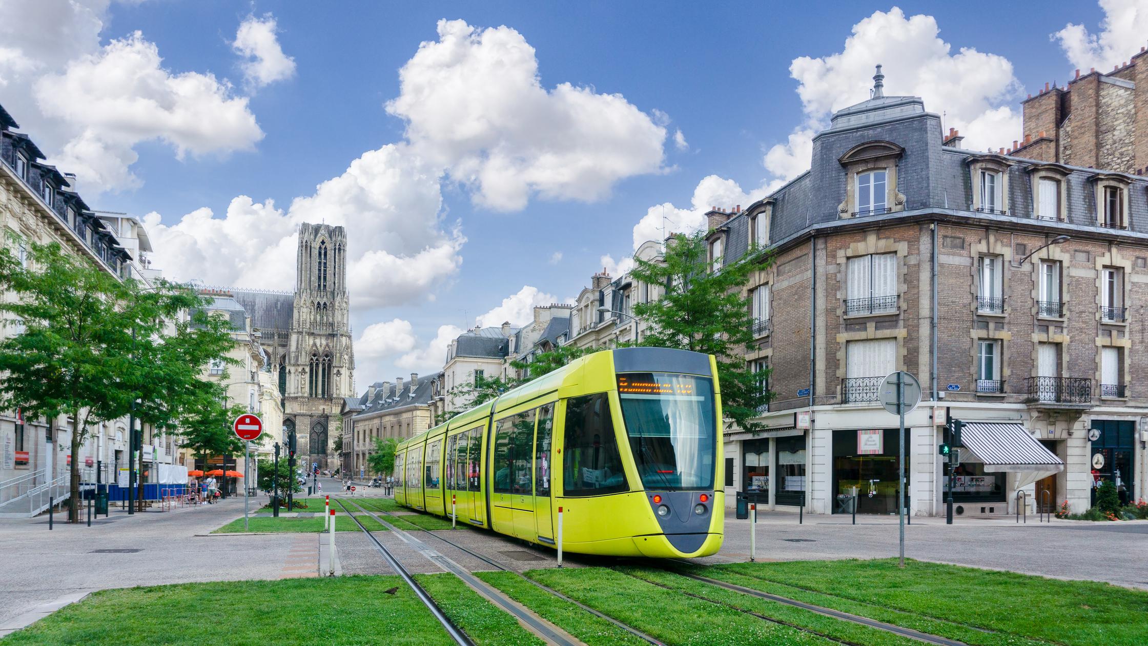 Tram in city with grass and buildings