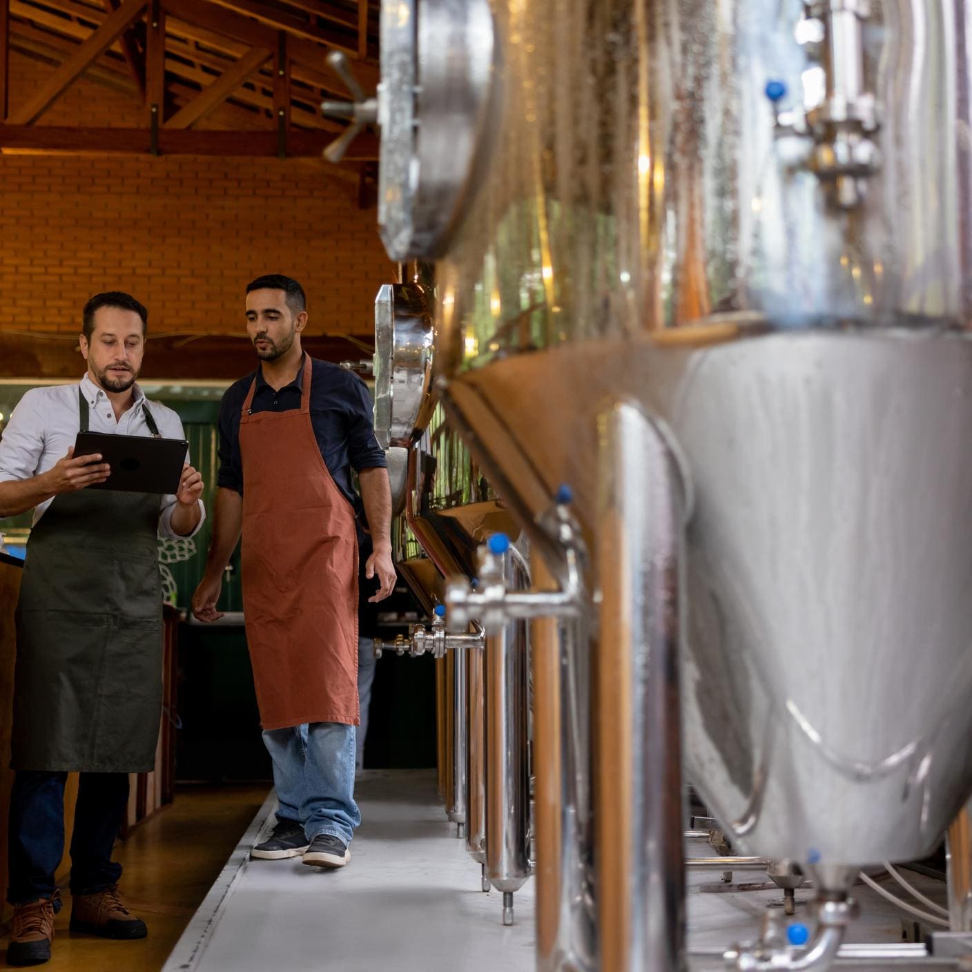 Men working at a brewery and controlling the production line using a tablet computer