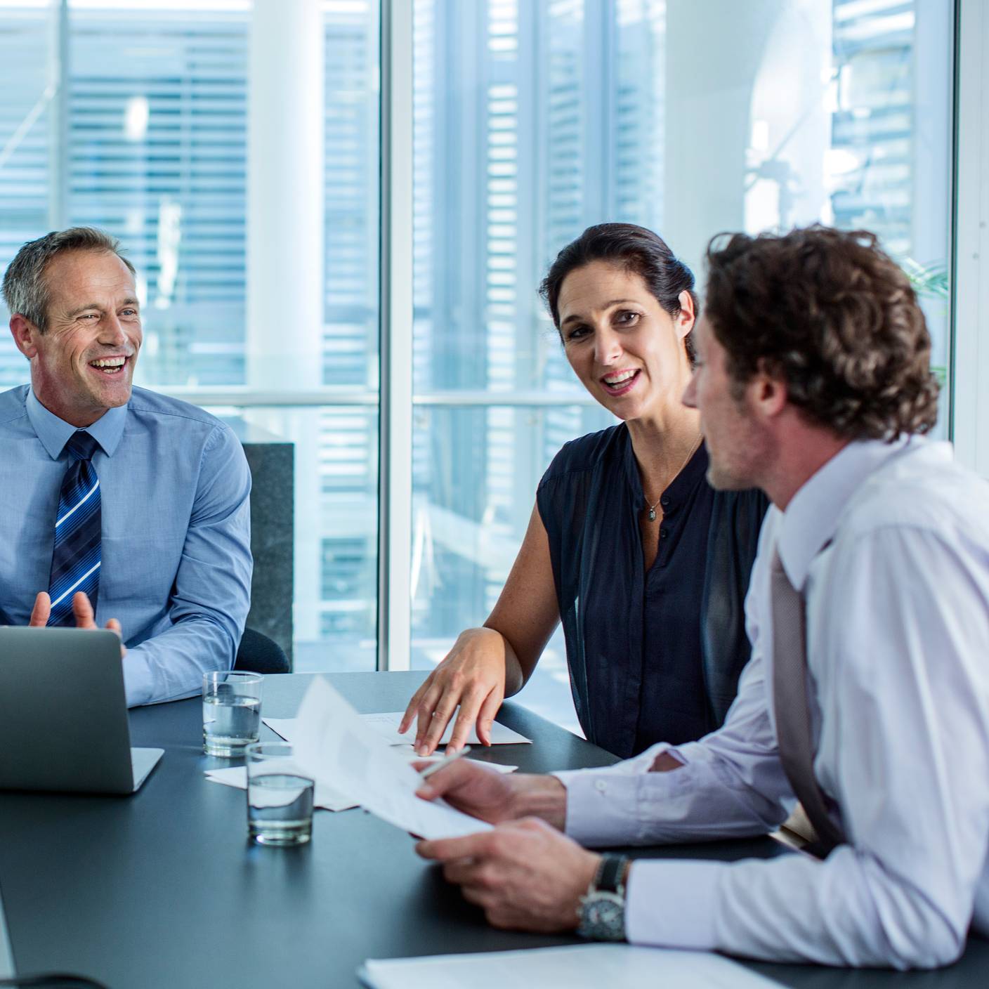 Happy business professionals discussing at conference table in office.