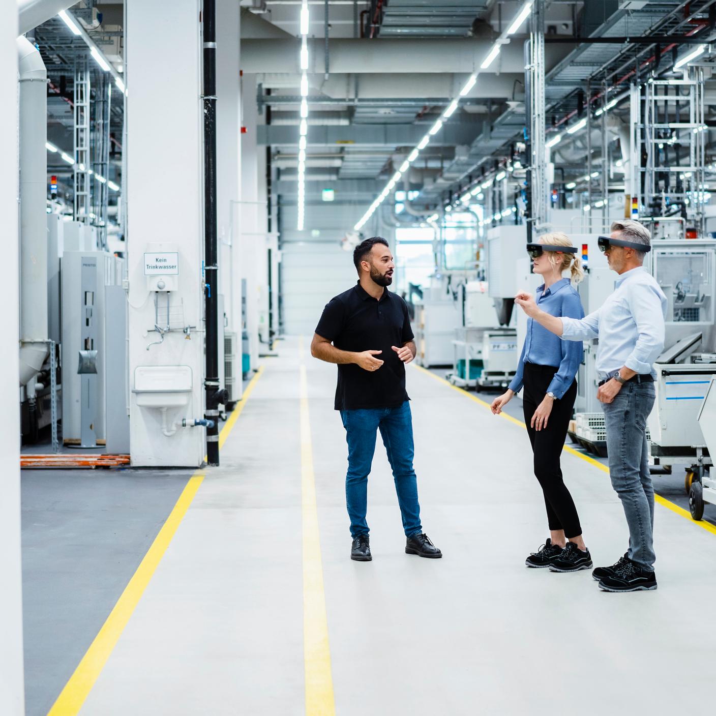 Engineer discussing with businessman and businesswoman using augmented reality glasses in industry