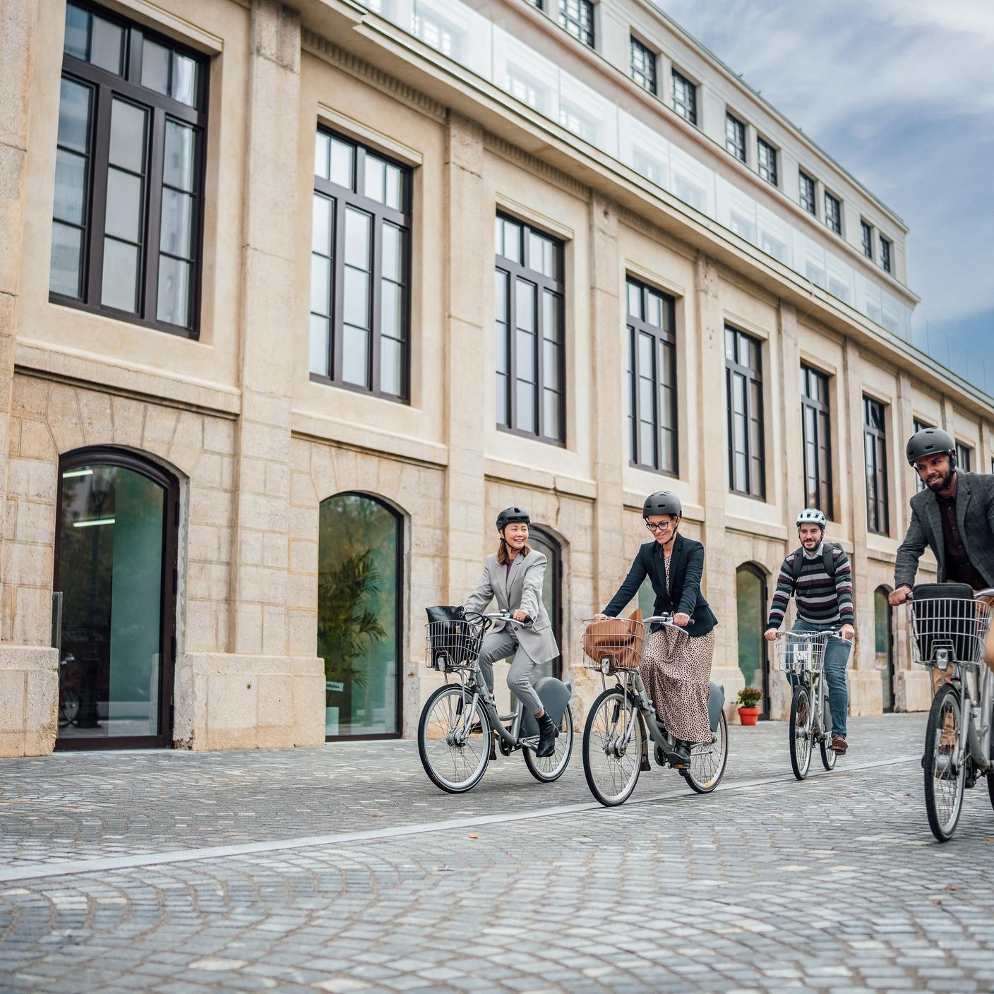 Un groupe diversifié de gens d’affaires se promène à vélo dans les rues dynamiques du centre-ville.