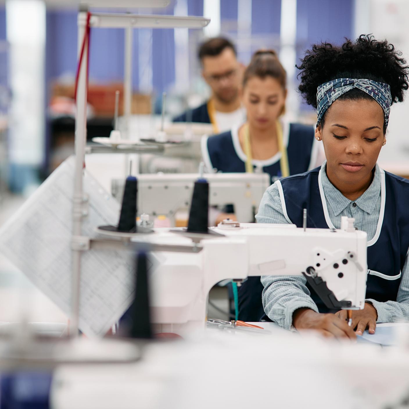 Une jeune femme afro-américaine cousant tout en travaillant comme couturière dans une usine de vêtements.