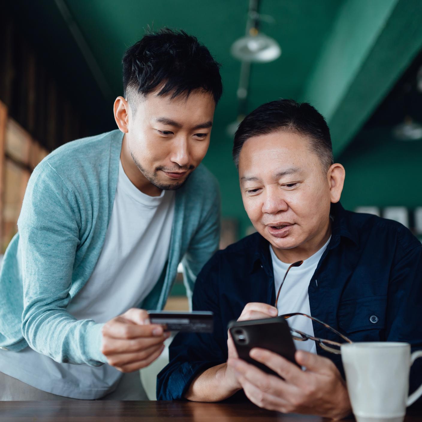 Joyful Asian senior father and son shopping online with mobile app