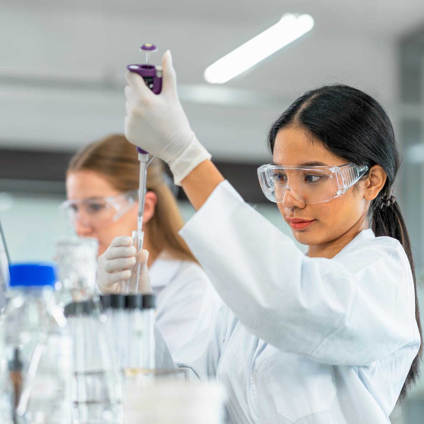 Biologists put chemical liquid with the pipette in a test tube inside a laboratory