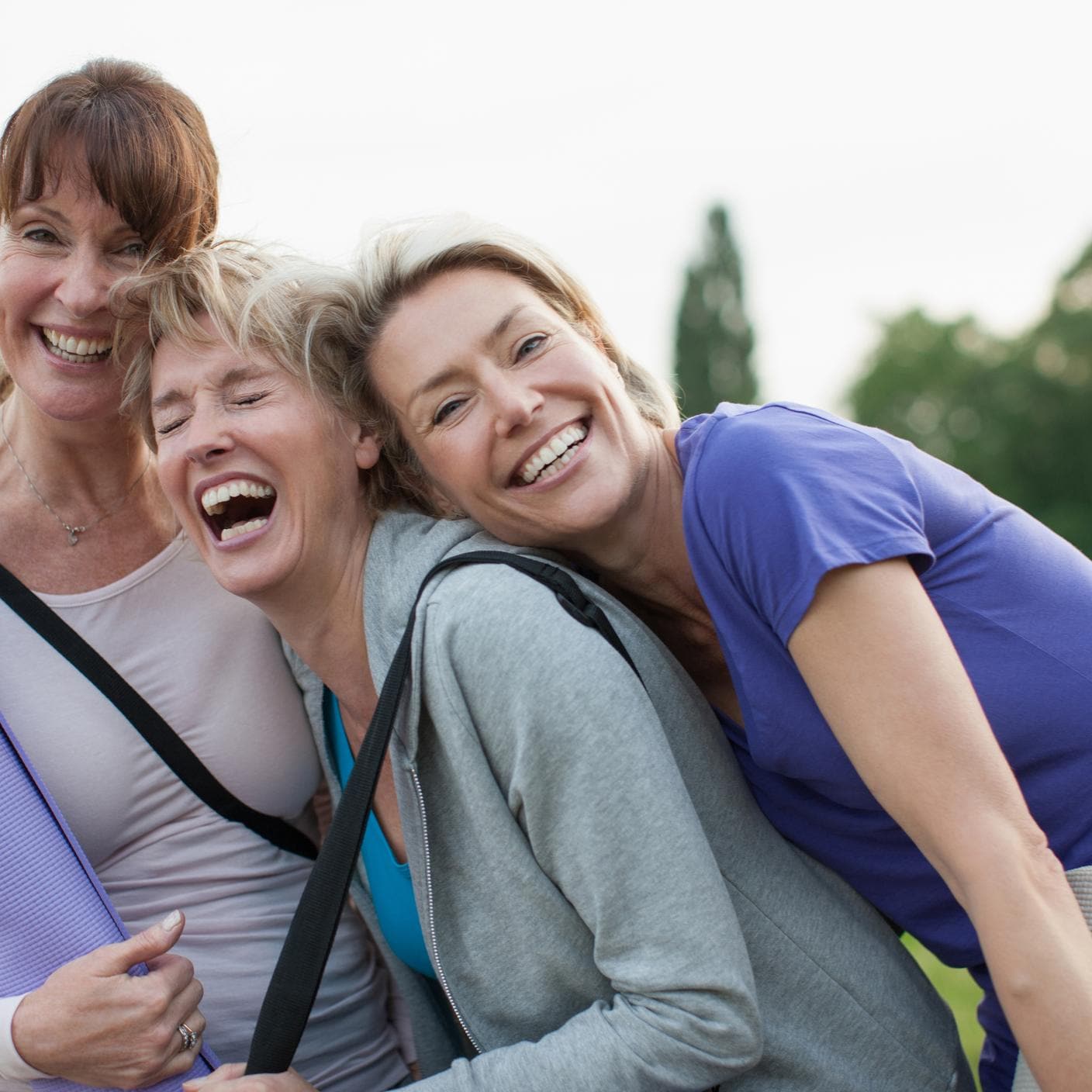 Smiling women holding yoga mats