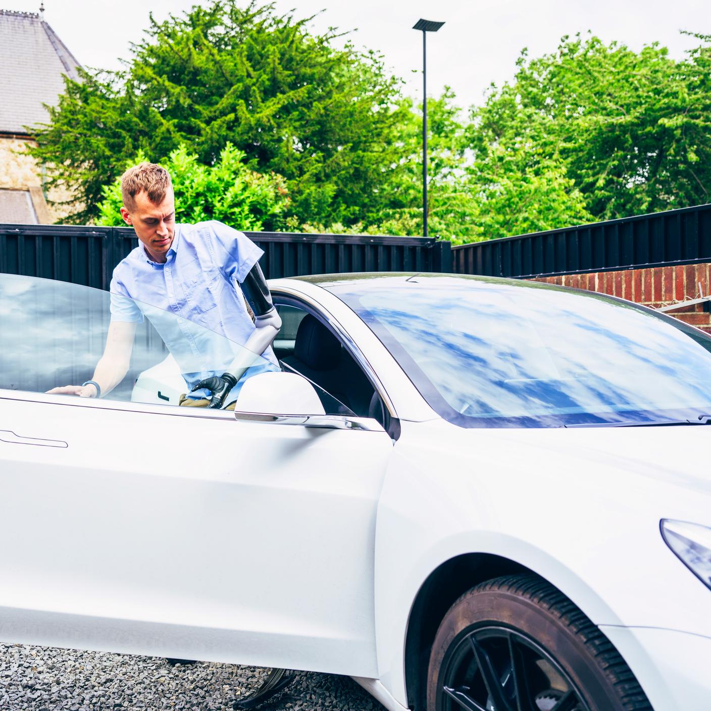 Man with prosthetic arm getting into his car to drive