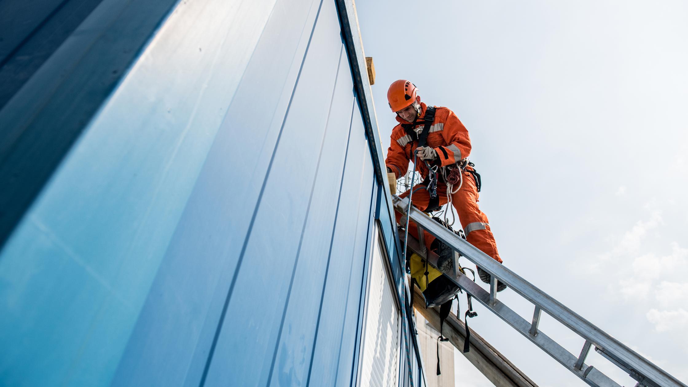 Construction worker on ladder next to building