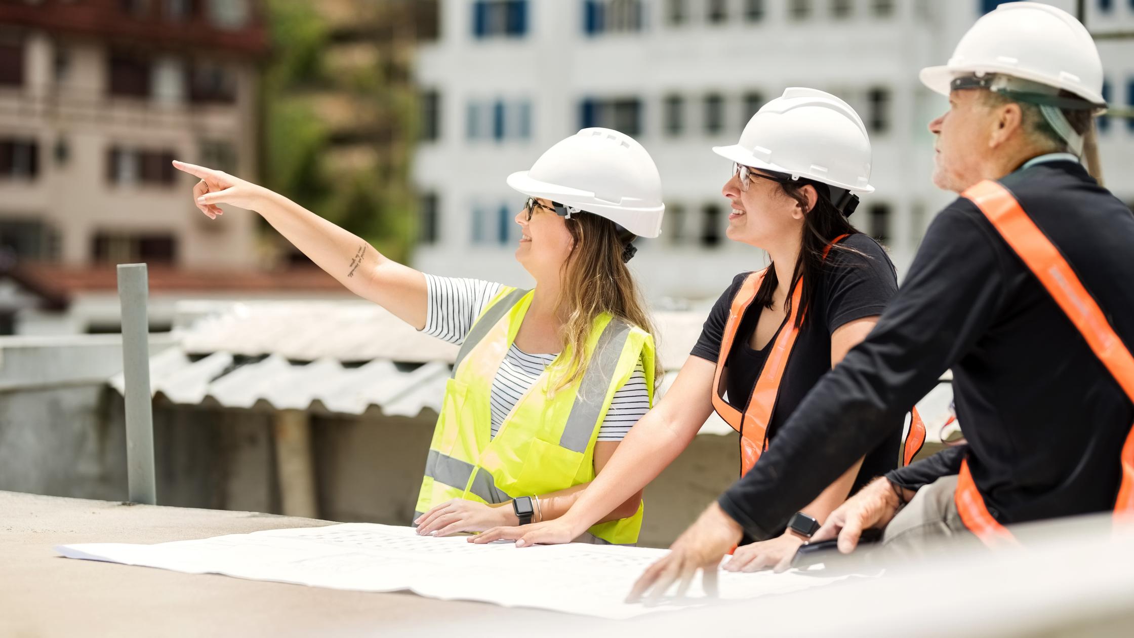 Construction workers and architect reviewing blueprint at construction site