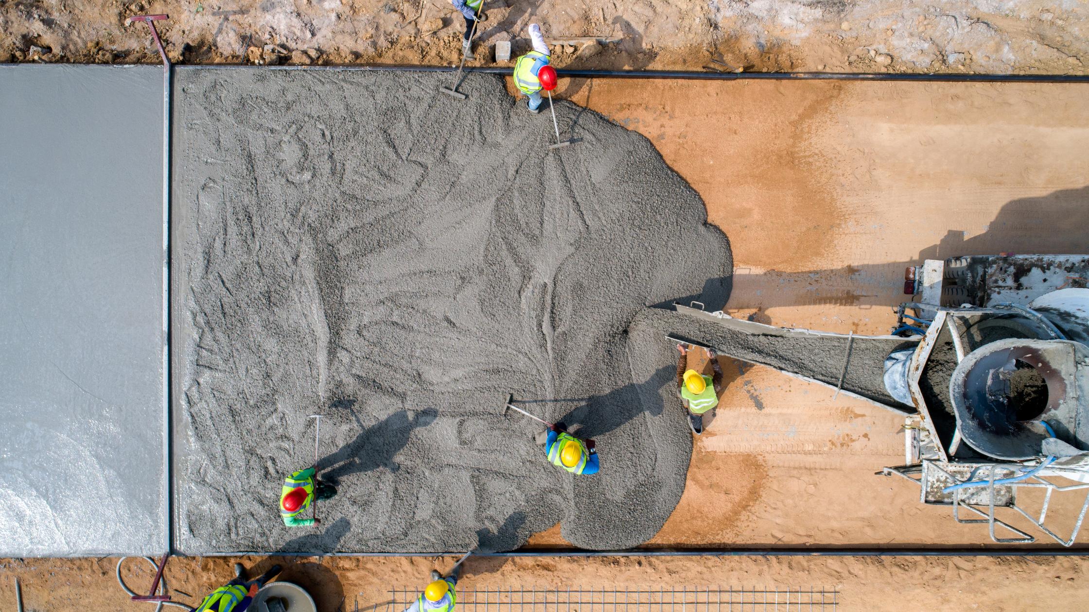 Construction workers pouring a wet concret at road construction site
