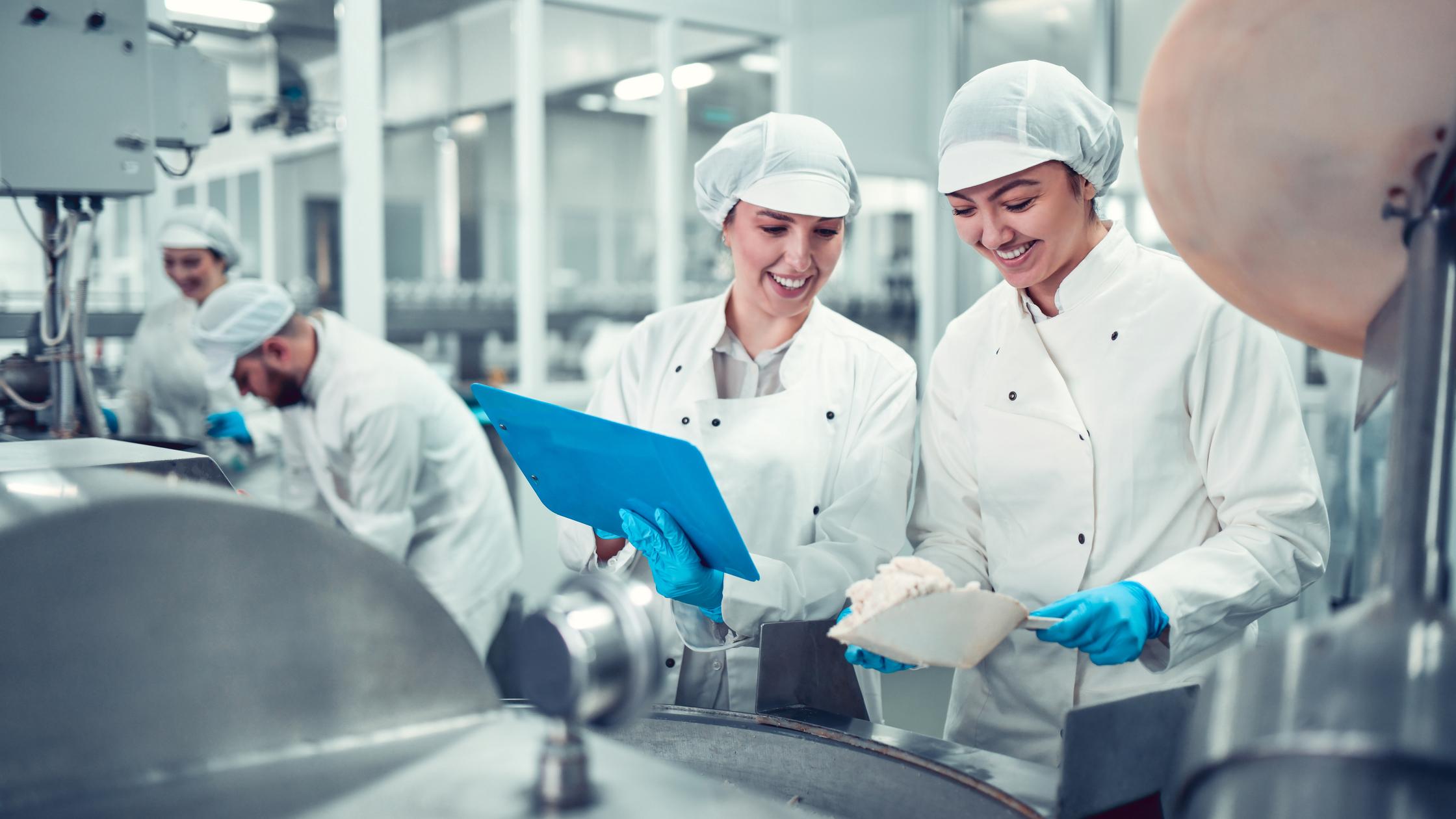 Factory Workers Filling Machine With Cottage Cheese For Stuffed Peppers In Jars