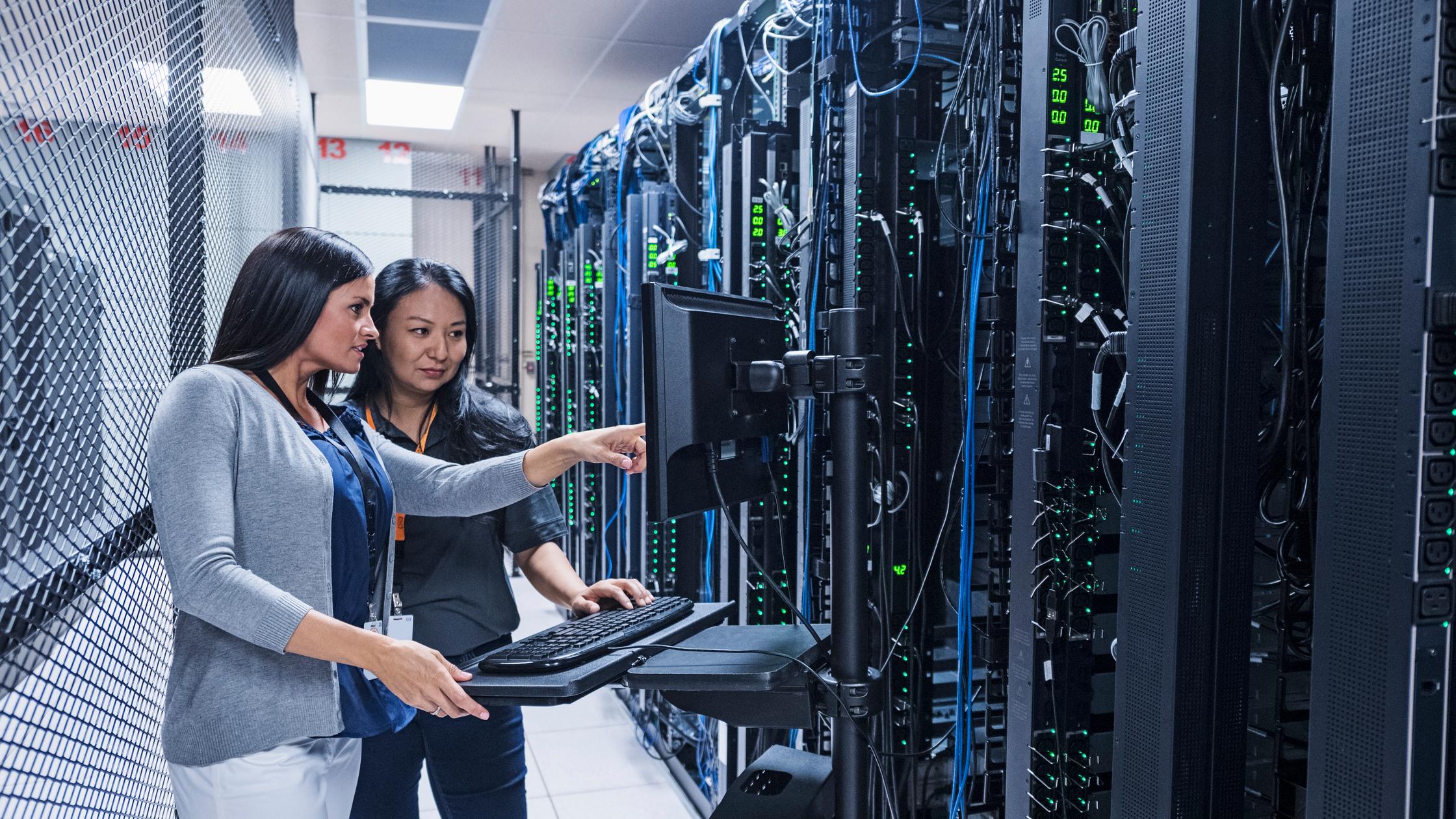 Two women working with computer in server room
