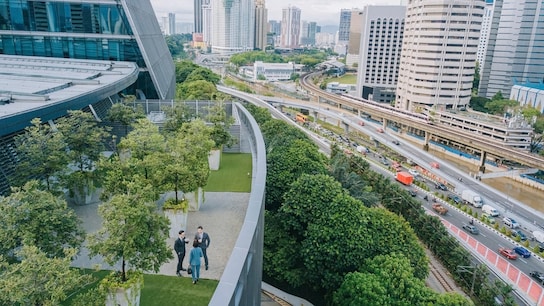 Three business person talking on roof top garden outside office building