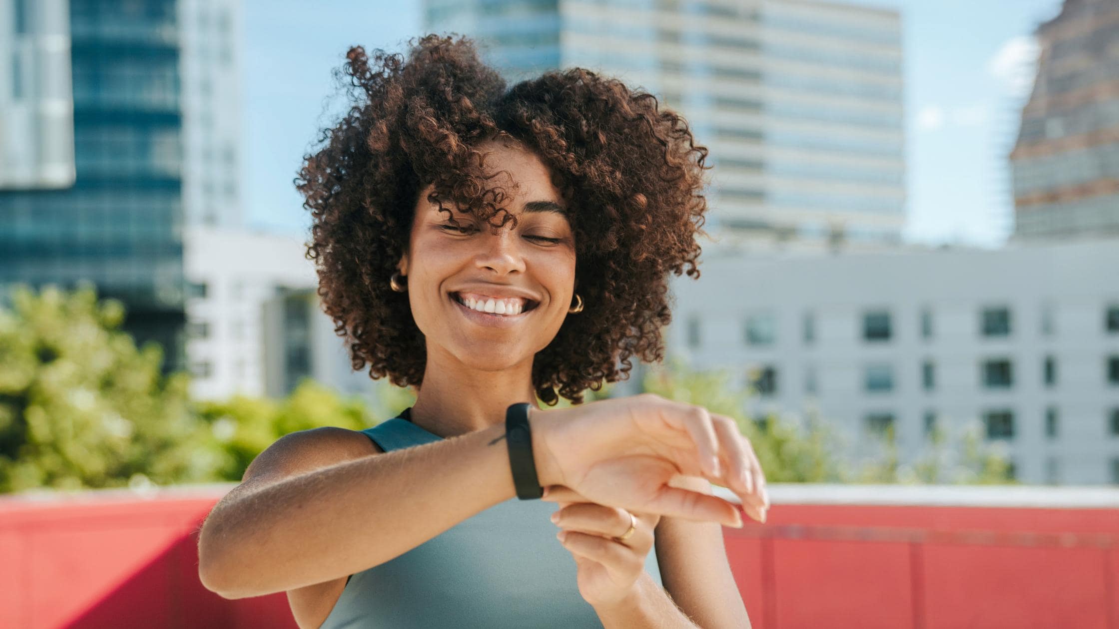 Woman looking at smart watch on a rooftop in Barcelona with buildings on the background.