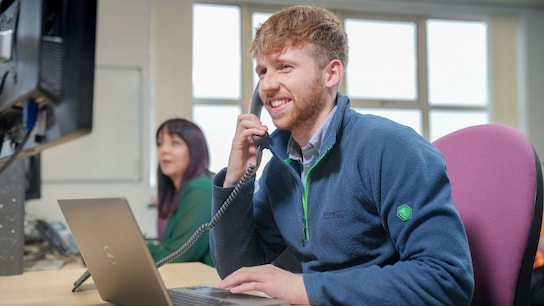 Operator speaking on the phone while using his laptop